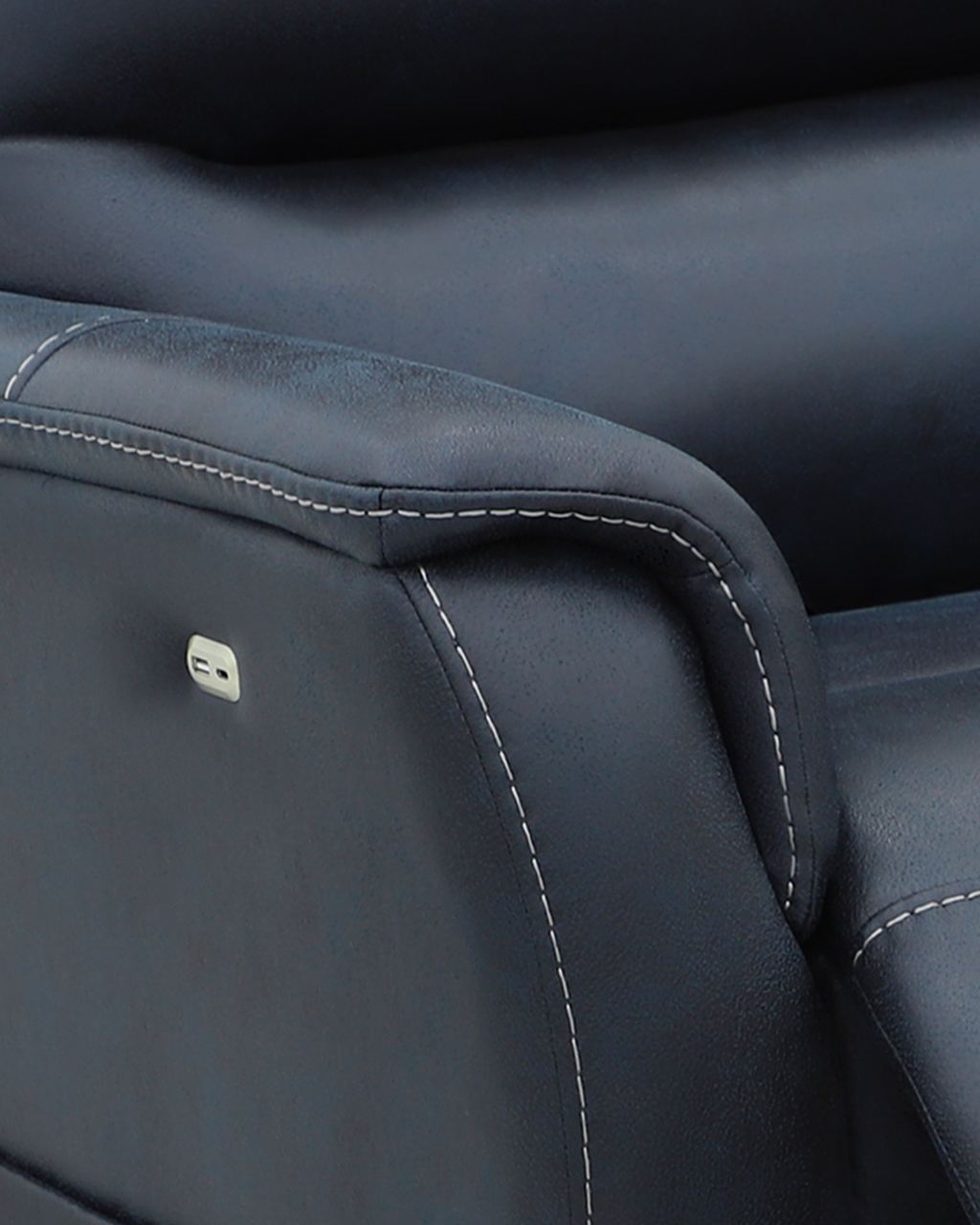 Close-up of a navy blue upholstered arm with contrast topstitching along the seam and a single recessed control button.