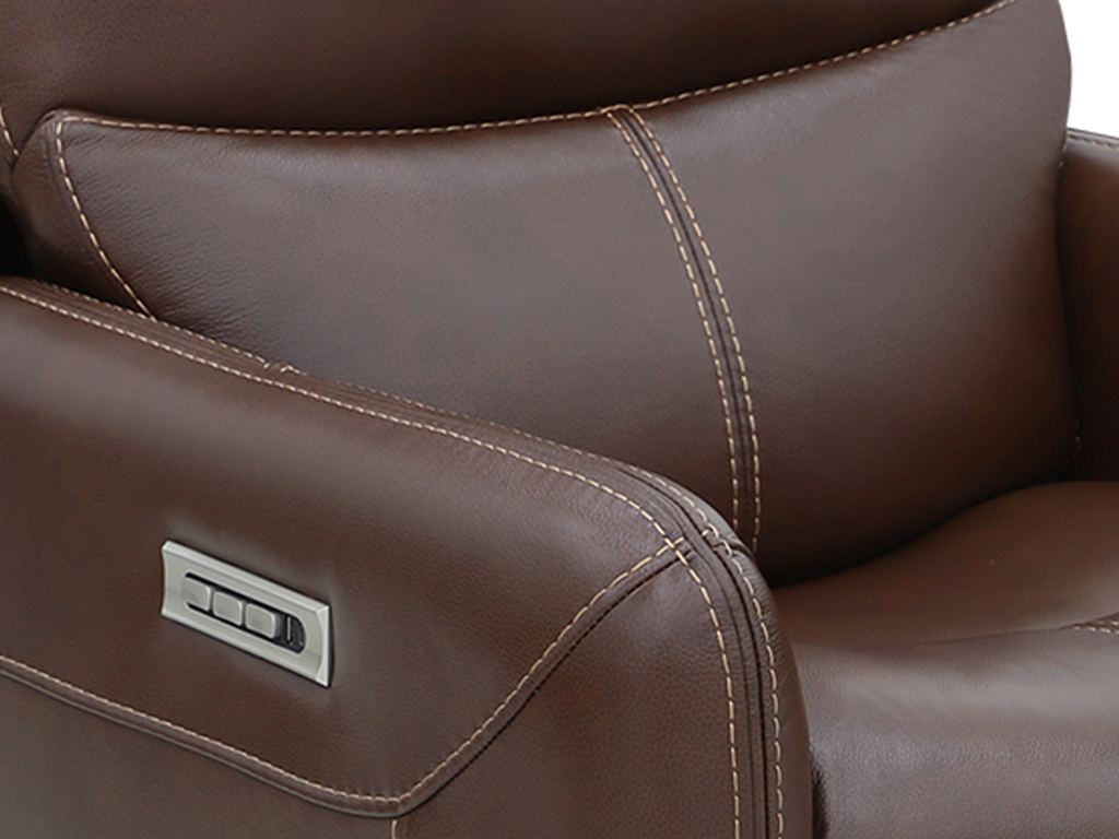 A brushed-metal arm control set into brown leather, with recline and headrest buttons and a USB port, beside a pillowed headrest.