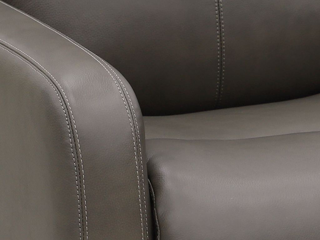 Close-up of a gray leather recliner arm, showing the natural grain and the topstitching along the seam.