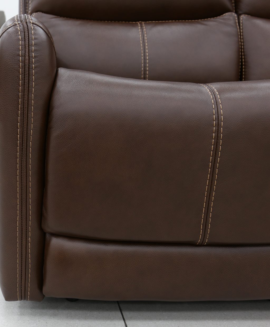 Detail of a top-grain leather sofa arm showing the pillowed roll and double stitch line.
