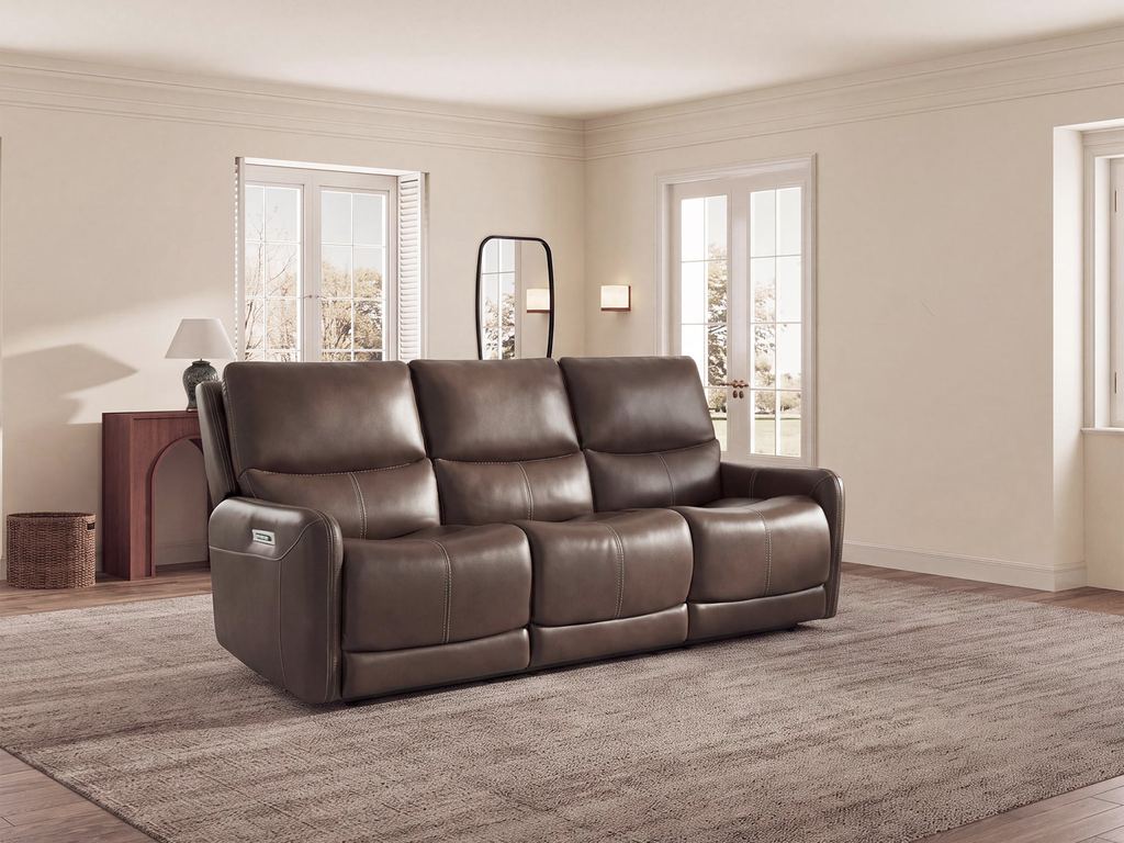 A three-seat brown leather power reclining sofa in a cream-walled room with tall windows and a wool rug.